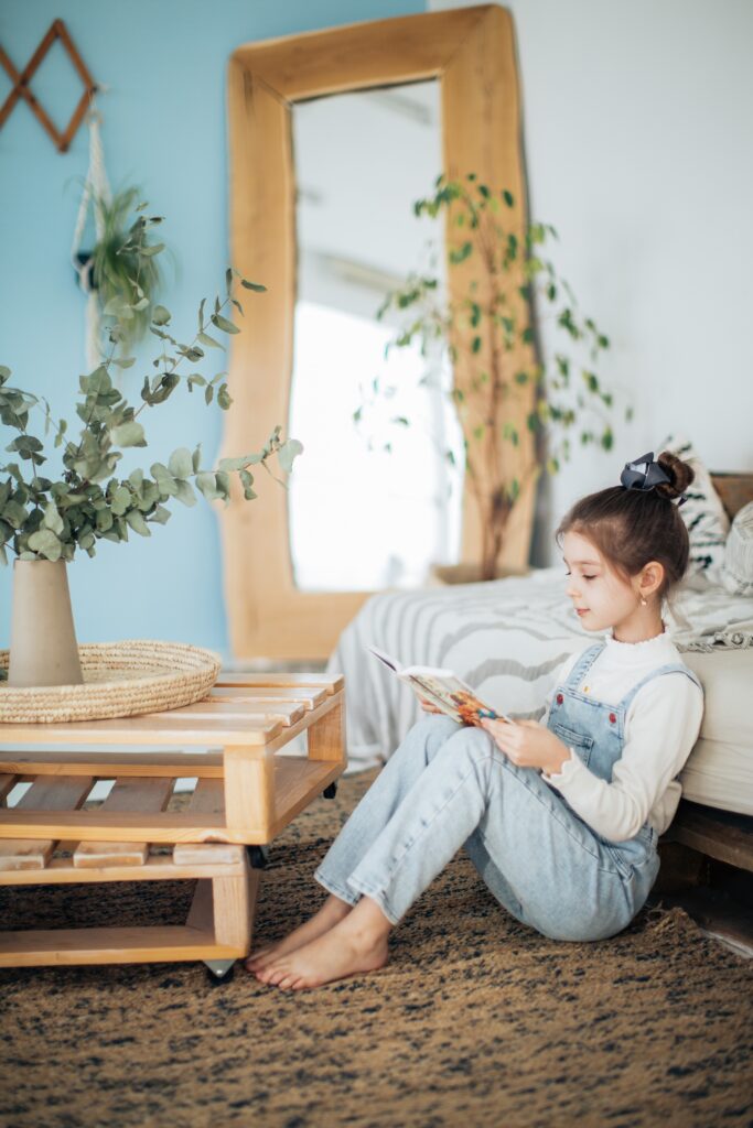 A girl sits on the carpet and reads a book