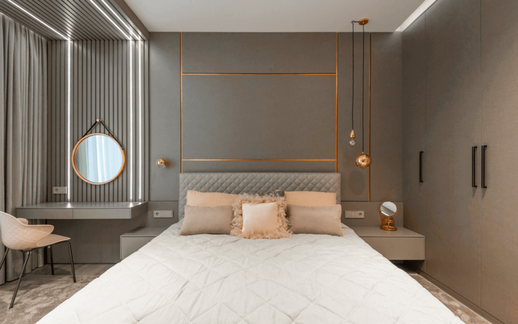 A bedroom with peach-coloured cushions on a light brown background and golden metal accents