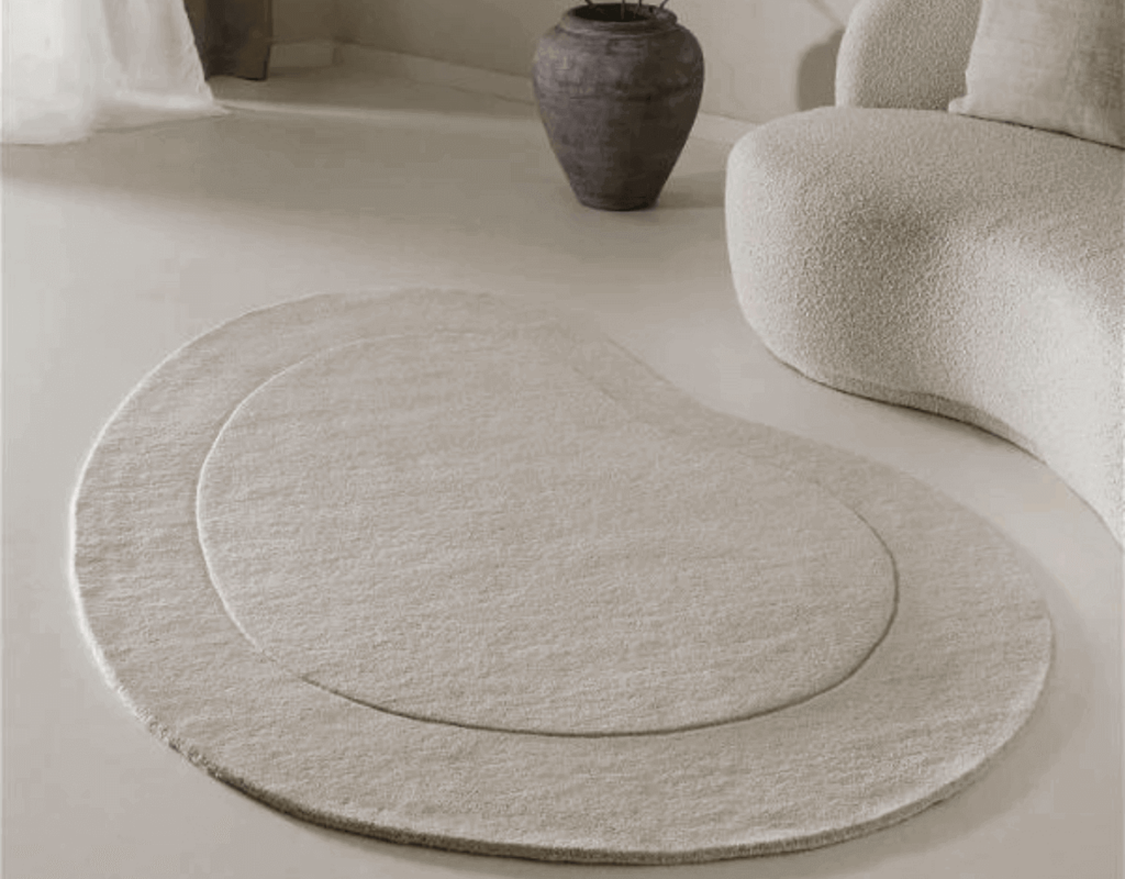 Elegant beige, abstract gevormd vloerkleed op een minimalistische witte vloer.