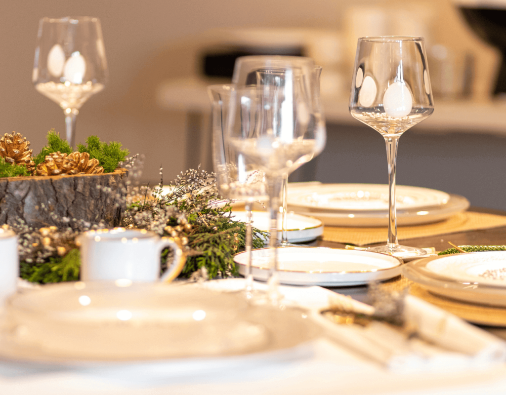 Elegant gedekte eettafel met kristallen glazen en met goud afgezette borden op een feestelijk gedekte tafel.