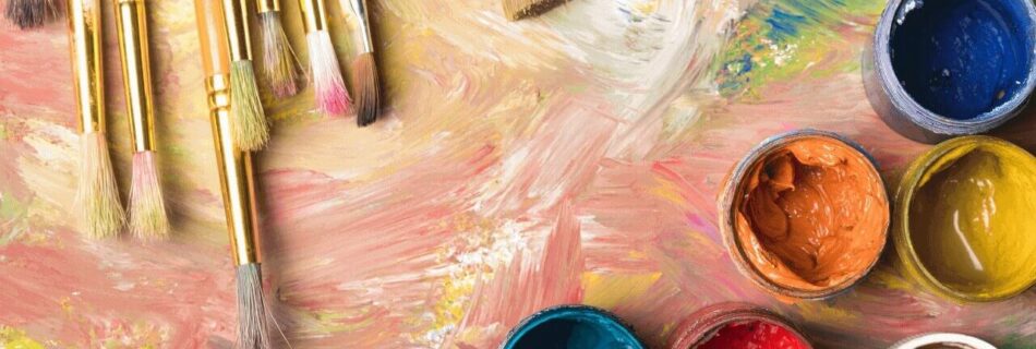 Artist's palette with brushes and open paint jars in vibrant colors.